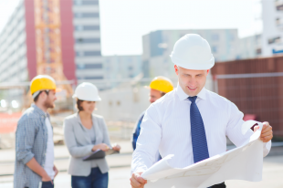 Business people wearing safety hats looking at blueprints